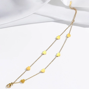 Detailed view of double-layered gold heart pendant bracelet on white silk background