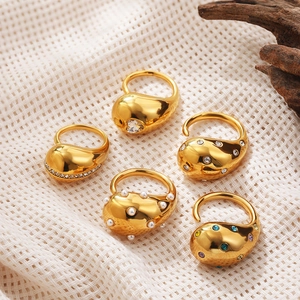 Set of gold teardrop rings with zircon and pearl on textured beige cloth