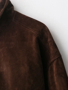 Detail of dark brown suede jacket showing shoulder stitching and collar texture
