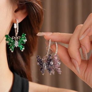 Macro detail of silver butterfly hoop earrings with vibrant colorful cubic zirconia