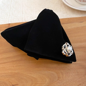 Détail d'une barrette en velours noir avec fleur de camélia en métal et perle