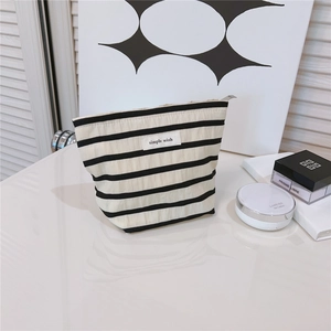 Macro detail of a striped canvas makeup bag featuring a simple wish label and zip closure