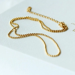 Makroaufnahme einer 18k Gold-Perlenkette mit verstellbarem Verschluss auf weißer Karte