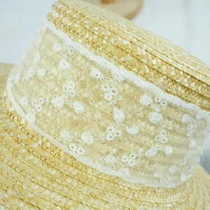 Close-up of fine straw weave and white lace embroidery detail on elegant sun hat