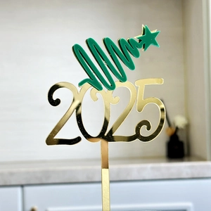 Détail du cake topper 2025 en acrylique doré avec motif d'arbre de Noël vert vif