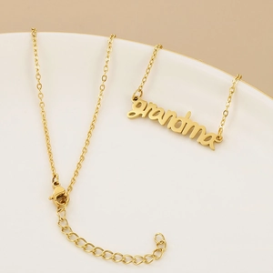Macro detail of golden cursive grandma pendant with lobster clasp and extension chain