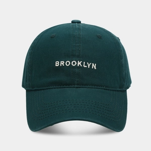 Detail of white Brooklyn 3D embroidery on deep green cotton twill baseball cap