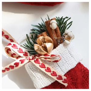 Detail of Christmas stocking with heart bow, pine needles, and golden dried nut