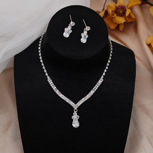 Macro detail of silver V-shaped necklace with water-drop pendant and matching earrings