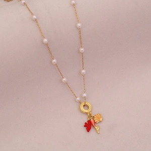 Detail of gold necklace featuring small pearls, red coral, and ocean shell charms