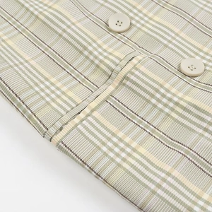 Detailed view of green and yellow plaid woven fabric with two light round buttons