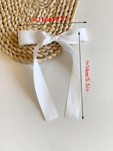 Detail showing white satin bow hair clip dimensions 11cm by 14cm with silky texture