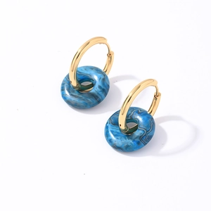Détail de boucles d'oreilles créoles dorées en acier avec breloques marbrées bleues