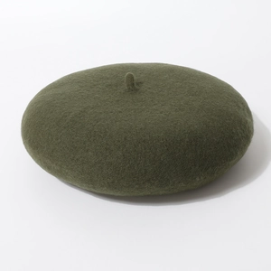 Detail van een donkergroene wollen vilten baret met dikke textuur en klassiek puntje