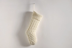 Close-up of white cable knit Christmas stocking with textured patterns and hanging loop