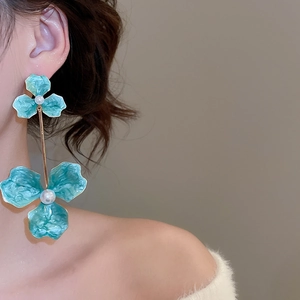 Detail of long floral drop earrings with green petals and pearls on a model