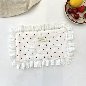 Detailed macro shot of white lace napkin featuring red hearts and a small woven label