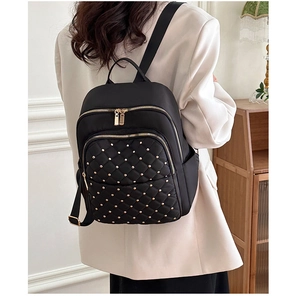 Dettaglio dello zaino in nylon nero con motivo a rombi trapuntato e borchie dorate decorative
