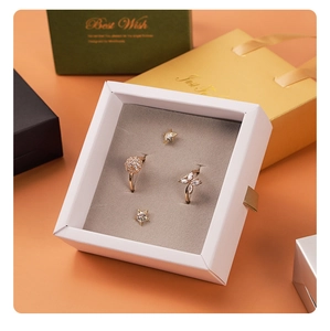 Detailed view of rose gold rings and star earrings set in a luxury orange gift box