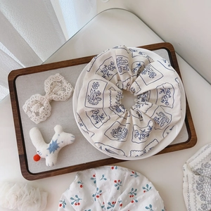 Floral print cotton scrunchie with blue patterns on cream fabric in an aesthetic setup