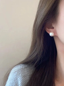 Detail showing classic single pearl stud earring with soft pinkish luster on model
