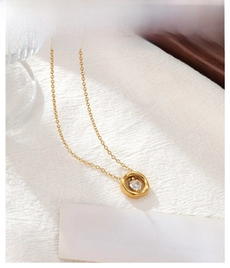 Détail d'un collier doré avec pendentif anneau et zircone en forme de cœur
