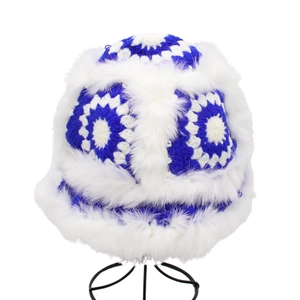 Blue and white crochet bucket hat with plush faux fur trim on a display stand