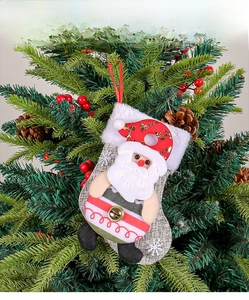 Detail of burlap Santa stocking with metal bell hanging on a festive Christmas tree