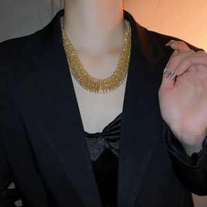 Close-up of a layered gold spiked collar necklace worn with a stylish black blazer