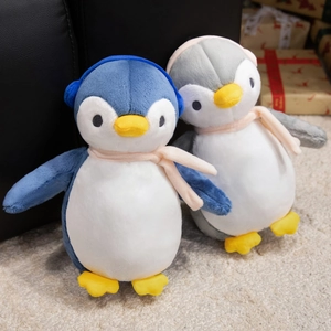 Close-up of blue and gray plush penguins with scarves and earmuffs on soft carpet