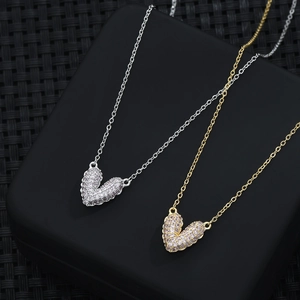 Detalle macro de collares de corazón en oro y plata con micro-pavé de circonitas en negro
