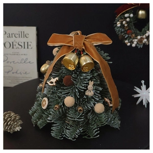 Detailed view of mini Christmas tree with velvet bow, bells and tiny colorful ornaments