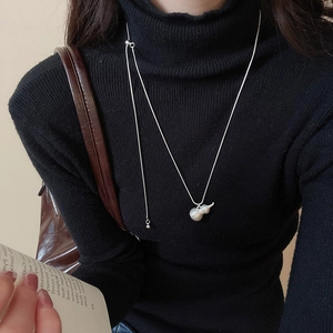Collana con ciondolo a forma di zucca in argento spazzolato su un maglione nero