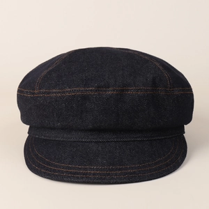 Detail of dark blue denim newsboy cap with contrasting yellow stitching and soft brim