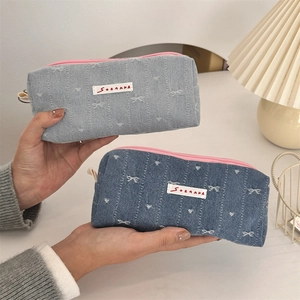 Close-up of denim bow pencil cases with pink zipper and embroidered butterfly details