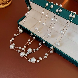 Double-layered gold plated pearl necklace displayed on an elegant dark green jewelry box