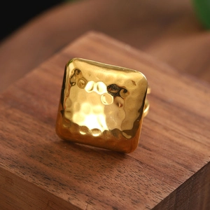 Vintage golden geometric square ring with hand-hammered texture on dark wood stand