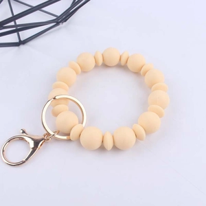 Dettaglio del portachiavi a bracciale in silicone crema con moschettone dorato su sfondo bianco