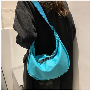 Detail view of bright blue nylon dumpling crossbody bag with adjustable wide fabric strap