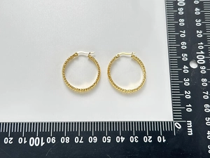 Vue macro de boucles d'oreilles créoles dorées de 30mm avec texture en spirale
