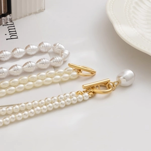 Detail of multi-layered pearl necklace with golden OT clasp and baroque heart pendant