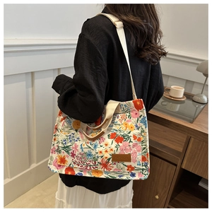 Detail of floral canvas tote bag with brown leather label and adjustable shoulder strap