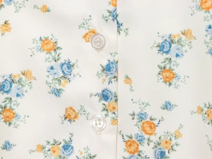 Détail macro du tissu popeline floral avec boutons blancs à quatre trous et imprimé