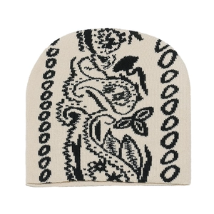 Détail du bonnet en maille beige avec motifs paisley noirs et textures de chaînes tissées