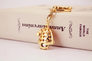 Detail of a gold metal Christmas hat keychain featuring a heart cutout and crystal rhinestone
