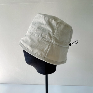 Light gray bucket hat with adjustable drawstring and side logo patch for women