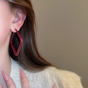 Close-up of diamond-shaped dark red hoops paired with an off-white knit sweater