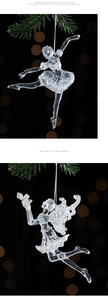 Clear acrylic ballet dancer and angel ornaments hanging from a pine branch with bokeh lights
