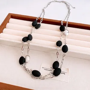 Vintage layered chain necklace with silver oval beads and black matte accents on a tray