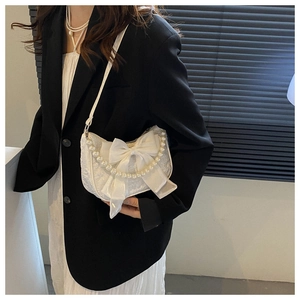 Fashionable white half-moon bag with bow and pearl chain shown on female model